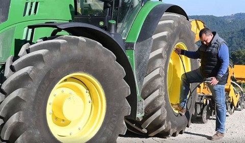 person standing against tractor wheel
